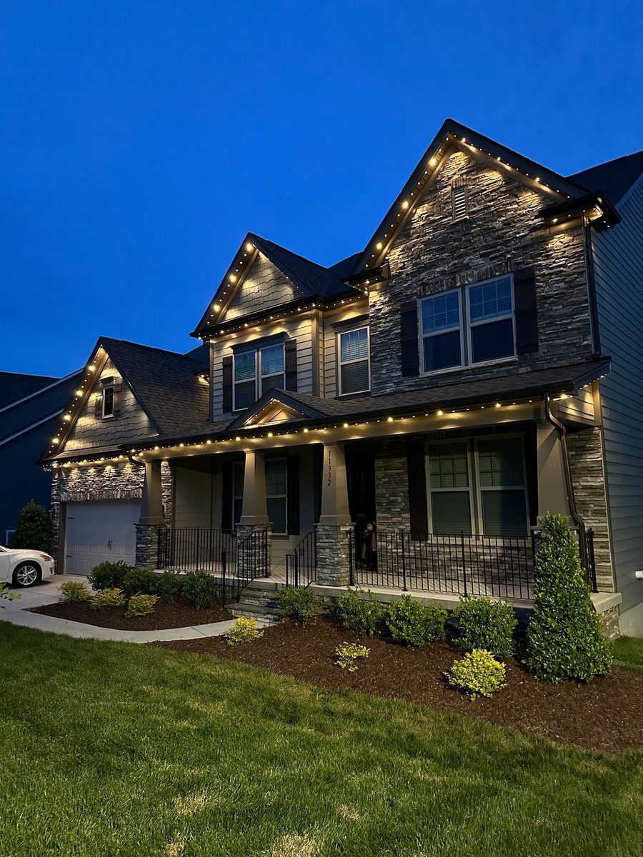 Home at dusk with warm white permanent lighting tracing the roofline